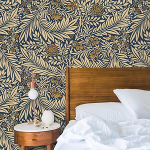 May include: A white bed with a wooden headboard and white bedding. The wall behind the bed is covered in a blue and gold floral wallpaper.
