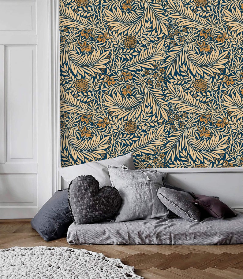 May include: A bedroom with a blue and cream floral wallpaper. The bed is covered with a gray blanket and has several gray pillows. A white knitted rug is on the floor.