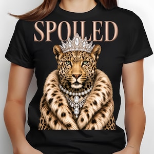 Może przedstawiać: Czarny t-shirt z ilustracją lamparta w koronie i naszyjniku. Lampart ma szal z futra. Słowo "SPOILED" jest wydrukowane nad lampartem złotymi literami.