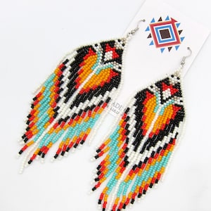 May include: A pair of long, beaded earrings with a geometric pattern in black, white, orange, red, and turquoise. The earrings are made of seed beads and have a fringe design.