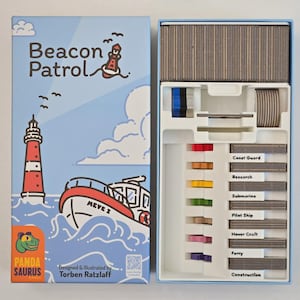 May include: A board game box and its contents are displayed. The box, titled "Beacon Patrol," features a lighthouse, boat, and the Panda Saurus logo. Inside, the game includes cards and colorful game pieces.