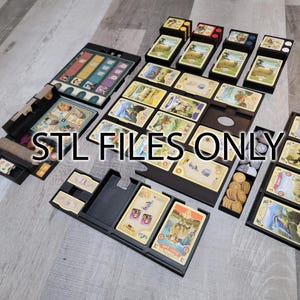 May include: A black organizer for the board game "The Voyages of Marco Polo" with compartments for cards, tokens, and dice. The organizer is made of 3D printed plastic and is designed to fit the game's components.