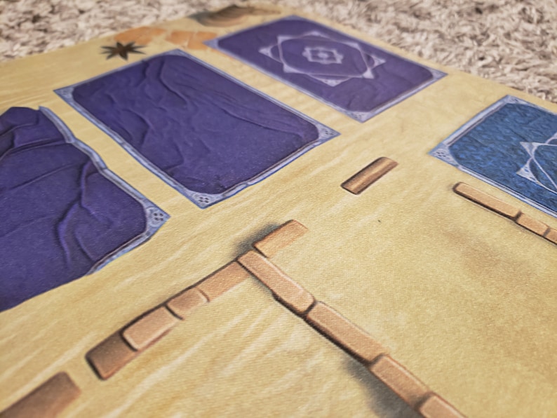 Peut inclure: Gros plan sur un plateau de jeu avec des tuiles bleues et violettes, et des pi&egrave;ces en bois brun. Le plateau est fait d'un mat&eacute;riau brun clair et a une surface textur&eacute;e.