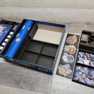 Peut inclure: Une bo&icirc;te de jeu noire et bleue avec un insert personnalis&eacute; pour organiser les pi&egrave;ces du jeu. La bo&icirc;te a un design bleu et noir avec le mot "ALIEN" sur le devant. L'insert a plusieurs compartiments pour ranger les pi&egrave;ces de jeu de diff&eacute;rentes tailles.