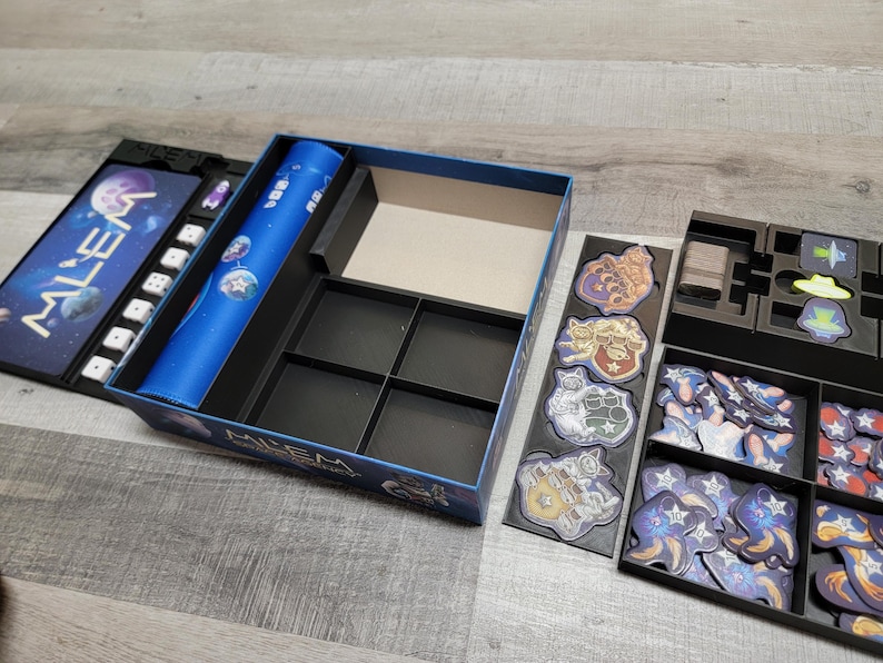 Peut inclure: Une bo&icirc;te de jeu noire et bleue avec un insert personnalis&eacute; pour organiser les pi&egrave;ces du jeu. La bo&icirc;te a un design bleu et noir avec le mot "ALIEN" sur le devant. L'insert a plusieurs compartiments pour ranger les pi&egrave;ces de jeu de diff&eacute;rentes tailles.