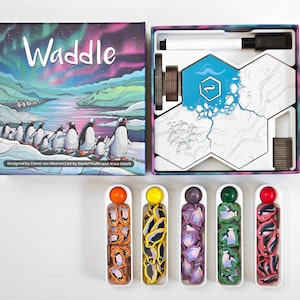 May include: The board game "Waddle" is displayed open, revealing game pieces and components. The box art features penguins and an aurora borealis scene. The game includes hexagonal tiles, a dry-erase marker, and penguin-shaped player tokens in various colors.