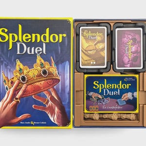 May include: The Splendor Duel board game box and open interior tray. The box cover features a gold crown held by two hands. The interior tray contains two decks of cards, a game board titled Splendor Duel The Counterfeiters, and small tokens.