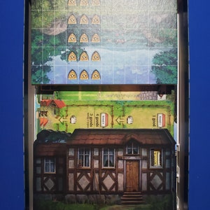 May include: A board game box with various game components. The box contains a game board with a landscape scene, wooden tokens, and cards. A detailed illustration of a house is visible. The game appears to be a strategy or resource management game.