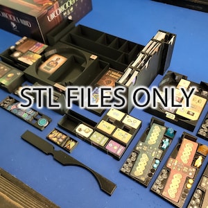 Puede incluir: Un organizador de impresión 3D negro para el juego de mesa "Unicorns United". El organizador incluye múltiples compartimentos para guardar los componentes del juego, incluidas las cartas, las fichas y los dados. El texto "STL FILES ONLY" está impreso en el organizador.