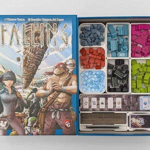 May include: A board game box titled FALLING with an illustrated cover featuring two characters and a large stone structure. The open box contains white plastic trays holding blue, red, pink, black, and green wooden tokens, blue gems, and card decks.