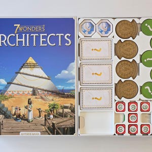 Puede incluir: La caja del juego de mesa "7 Wonders Architects" se muestra abierta, revelando los componentes del juego. La portada presenta una pirámide y el título del juego. Dentro, hay fichas, cartas y piezas del juego.
