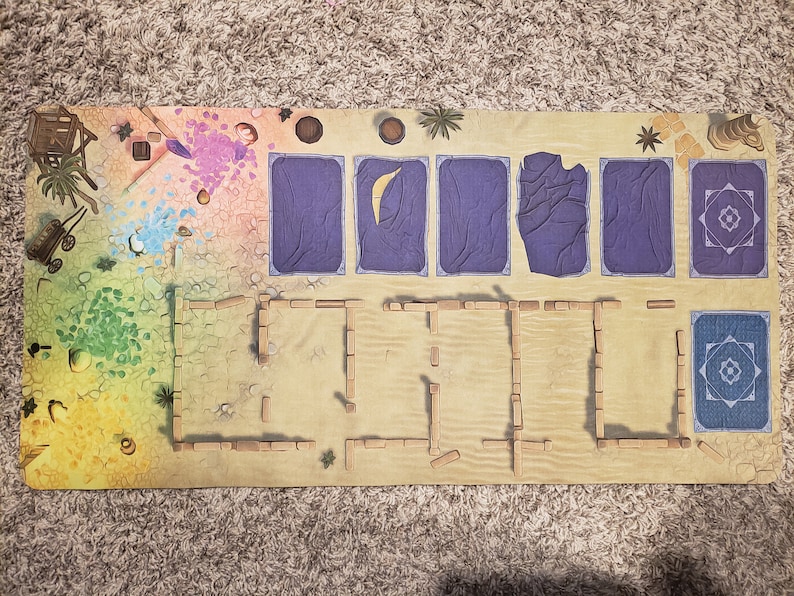 Peut inclure: Un plateau de jeu sur le th&egrave;me du d&eacute;sert. Le plateau est fait d'un mat&eacute;riau brun clair et pr&eacute;sente une vari&eacute;t&eacute; d'&eacute;l&eacute;ments color&eacute;s, notamment une tuile bleu et blanche, une tuile violette et une tuile verte. Le plateau pr&eacute;sente &eacute;galement une structure en bois avec un toit brun.