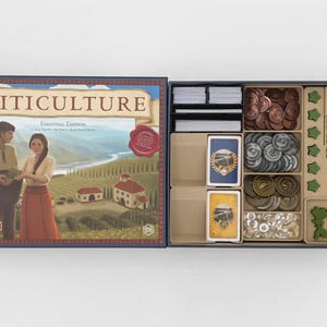 May include: The Viticulture Essential Edition board game box is open, revealing a game board lid featuring a vineyard illustration and a storage tray containing stacks of cards, various metal-colored coins, and green wooden game pieces.