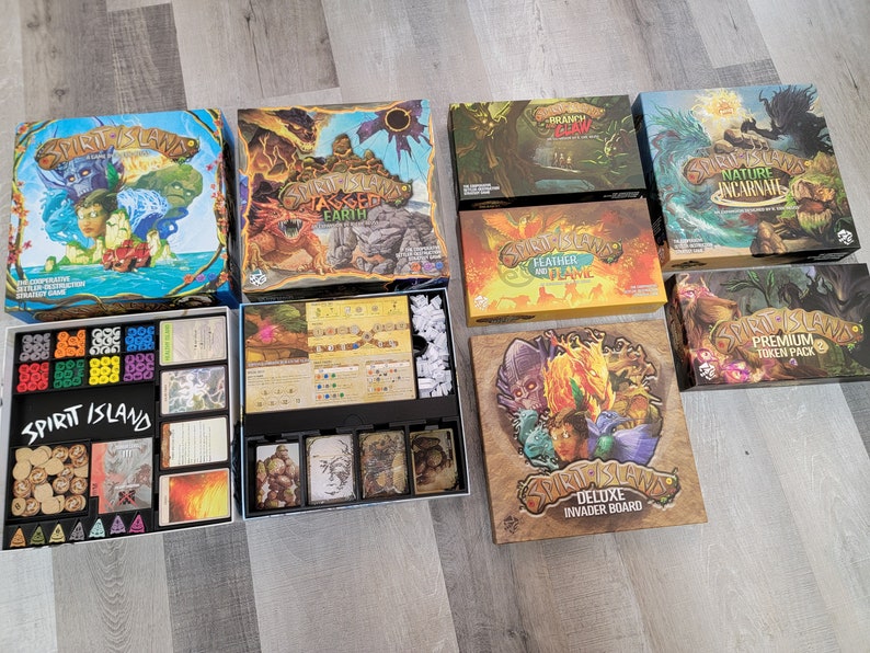 May include: A collection of Spirit Island board game expansions, including "Nature Incarnate", "Jagged Earth", "Feather and Flame", "Premium Token Pack", and "Deluxe Invader Board".