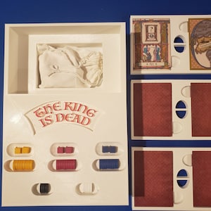 以下が含まれることがあります： 「The King Is Dead」と印刷された白いゲームボード。ボードには、黄色、赤、青のトークンを含むゲームピースを収納するためのコンパートメントがあります。また、地図と中世のシーンが描かれたカードが2枚あります。