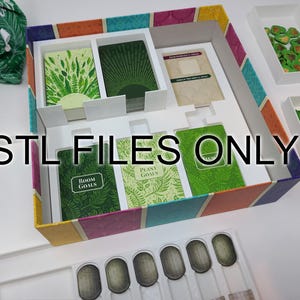 May include: A colorful board game box with various components. The box contains cards with plant-themed designs, wooden plant tokens, and other game pieces. The text "STL FILES ONLY" is printed on the image.