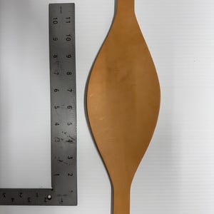 Puede incluir: Una correa de cuero marrón claro con un extremo puntiagudo. La correa mide aproximadamente 28 cm de largo y 5 cm de ancho en su punto más ancho.