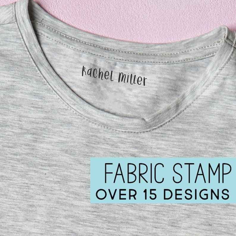 Może przedstawiać: Zbliżenie szarej koszulki z napisem "Rachel Miller" wydrukowanym w pobliżu kołnierza. Jasnoniebieski prostokąt poniżej zawiera napis "FABRIC STAMP OVER 15 DESIGNS". Tło jest r&oacute;żowe.