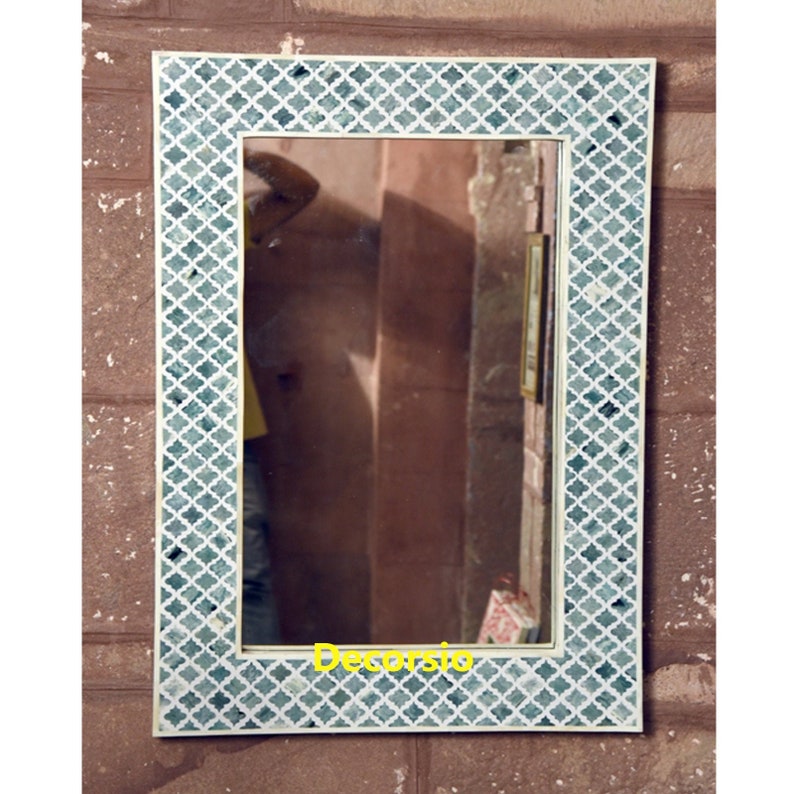 May include: A rectangular wall mirror featuring a wide frame with a repeating teal and white quatrefoil pattern. The reflective glass surface is centred within the decorative border, which displays a consistent geometric design throughout.