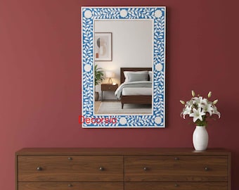 May include: A rectangular wall mirror featuring a blue and white floral inlay frame with a repeating vine and flower pattern. The mirror reflects a bedroom interior with a bed and nightstand. The word Decorsio is printed in red on the frame.