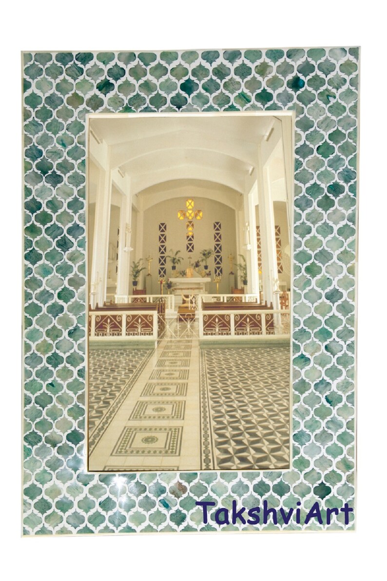 May include: A rectangular wall mirror featuring a frame with a repeating green and white quatrefoil pattern. The mirror reflects the interior of a church with pews, an altar, and a cross. The text TakshviArt is printed in blue at the bottom right.