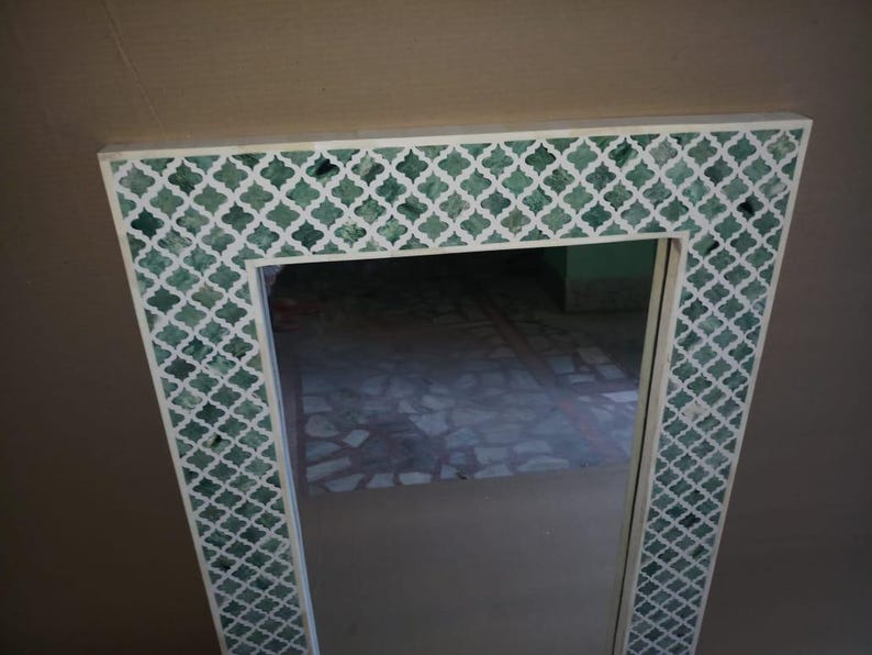 May include: A rectangular wall mirror featuring a wide frame with a white and green quatrefoil pattern. The frame consists of white lattice work inlaid over a deep green background, creating a repeating geometric design around the central glass.