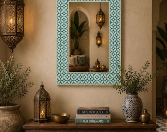 May include: A rectangular wall mirror featuring a frame with a repeating teal and cream geometric circle pattern. The mirror is mounted on a wall above a wooden console table, reflecting a room with a potted plant and hanging lanterns.