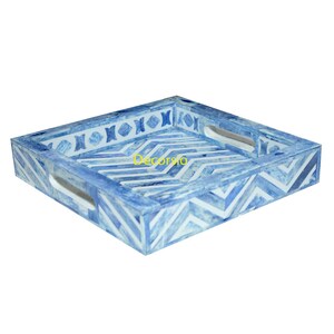 May include: A square serving tray with blue and white geometric patterns. The tray has two handles on the sides and a decorative border.