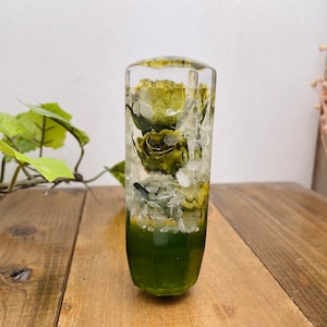May include: A clear glass gear shift knob with dried green flowers and white crystals inside. The knob is green at the bottom.