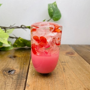 May include: A pink resin gear shift knob with pressed flowers inside. The flowers are white and red.