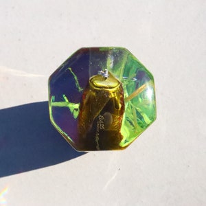 May include: A green, octagonal, glass paperweight with a gold beetle encased inside. The beetle has a label that reads "Realis - Ecuador".