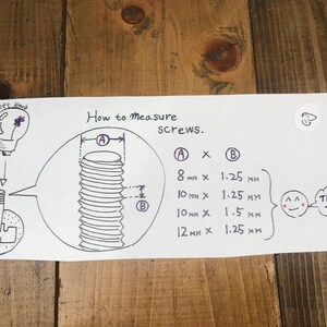 Pu&ograve; includere: Diagramma disegnato a mano che mostra come misurare le viti. Il diagramma mostra una vite con due misure etichettate come A e B. Il testo spiega che A &egrave; il diametro della vite e B &egrave; la lunghezza della vite. Il diagramma include anche una tabella con diverse dimensioni di viti, tra cui 8 mm x 1,25 mm, 10 mm x 1,25 mm, 10 mm x 1,5 mm e 12 mm x 1,25 mm.