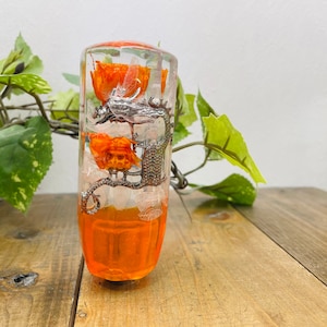 May include: A clear glass gear shift knob with orange resin and a silver dragon design. The resin contains dried orange flowers.