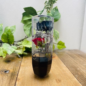 Könnte beinhalten: Ein transparenter Schaltknauf aus Harz mit schwarzen und roten Rosen im Inneren. Die Rosen sind konserviert und scheinen in dem Harz zu schweben. Der Knauf ist außen schwarz.