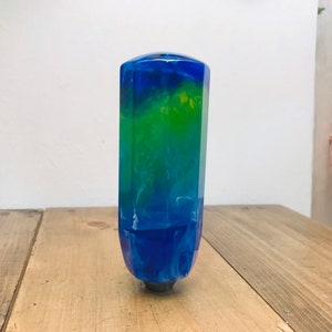 Peut inclure: Un pommeau de levier de vitesse hexagonal en résine bleu, vert et blanc.