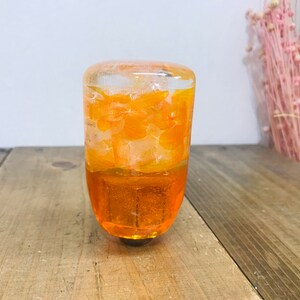 May include: Orange and clear resin gear shift knob with a swirl design.