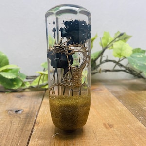 May include: A clear glass gear shift knob with a gold dragon design and black flowers inside. The base of the knob is filled with gold glitter.