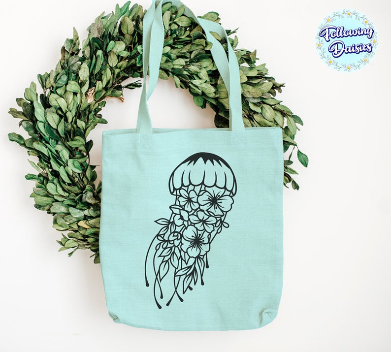 May include: A light blue tote bag with a black floral jellyfish design. The bag has two handles and is made of a soft, canvas-like material.