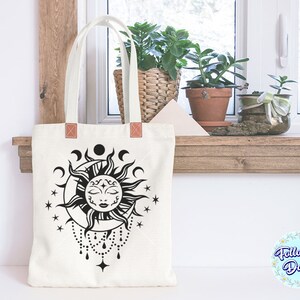 K&ouml;nnte beinhalten: Eine wei&szlig;e Einkaufstasche mit einer schwarz-wei&szlig;en Illustration einer Sonne und eines Mondes mit einem Gesicht. Die Sonne hat ein geschlossenes Auge und ein kleines L&auml;cheln. Die Einkaufstasche hat braune Ledergriffe.