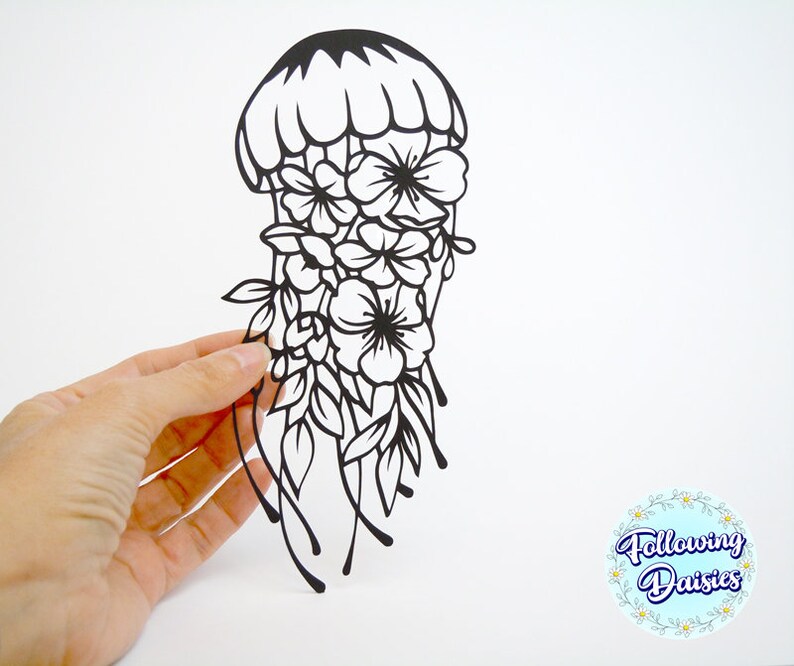 May include: Black paper cut-out of a jellyfish with flowers and leaves. The jellyfish is in the center of the image and is surrounded by flowers and leaves. The image is on a white background.