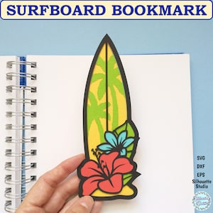 Puede incluir: Un marcapáginas de tabla de surf amarillo con palmeras verdes y una flor de hibisco roja. El marcapáginas está recortado en papel y tiene un contorno negro.