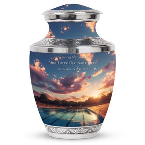 May include: Silver cremation urn with a sunset sky and swimming pool image. The urn has an inscription that reads "In Loving Memory Of Your Loved One Name Here May 16, 1969 - Oct 06, 2022".