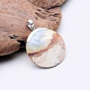 May include: A round, silver pendant with a white and brown seashell inlay. The pendant has a silver bail for attaching to a chain.