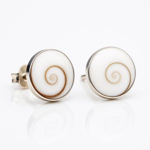 Puede incluir: Un par de pendientes de plata con incrustaciones de concha blanca con un patrón de espiral marrón.