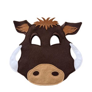 May include: A brown felt warthog mask with white tusks, tan snout, and tan ears. The mask has eye holes and a brown fringe on top. This costume accessory is suitable for children's play or themed events.