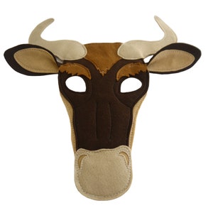 Może przedstawiać: Filcowa maska byka w odcieniach brązu, beżu i kremu. Maska posiada otwory na oczy, pysk i zakrzywione rogi. Maska jest przeznaczona do noszenia na twarzy.