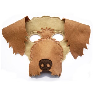 Può includere: Una maschera da cane fatta a mano in feltro marrone e beige. La maschera presenta grandi orecchie flosce, un muso dettagliato e cuciture intorno agli occhi e al muso. Perfetta per feste in costume o giochi fantasiosi.