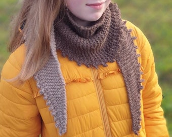 May include: A young person wearing a yellow jacket with a brown knitted scarf. The scarf has a scalloped edge.