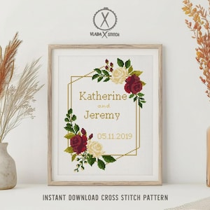 May include: A cross stitch pattern in a wooden frame featuring a gold geometric border, red and white roses, and green leaves. The text reads Katherine and Jeremy with the date 05.11.2019. The design is centered on a white background.