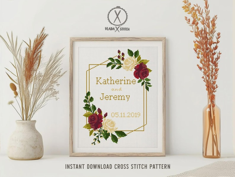 May include: A cross stitch pattern in a wooden frame featuring a gold geometric border, red and white roses, and green leaves. The text reads Katherine and Jeremy with the date 05.11.2019. The design is centered on a white background.